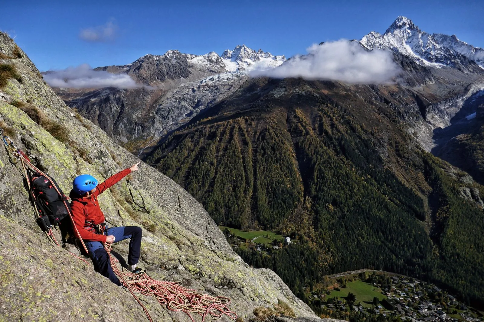 Julien en cordée, assis sur une dalle de granit, montre la vallée et les glaciers