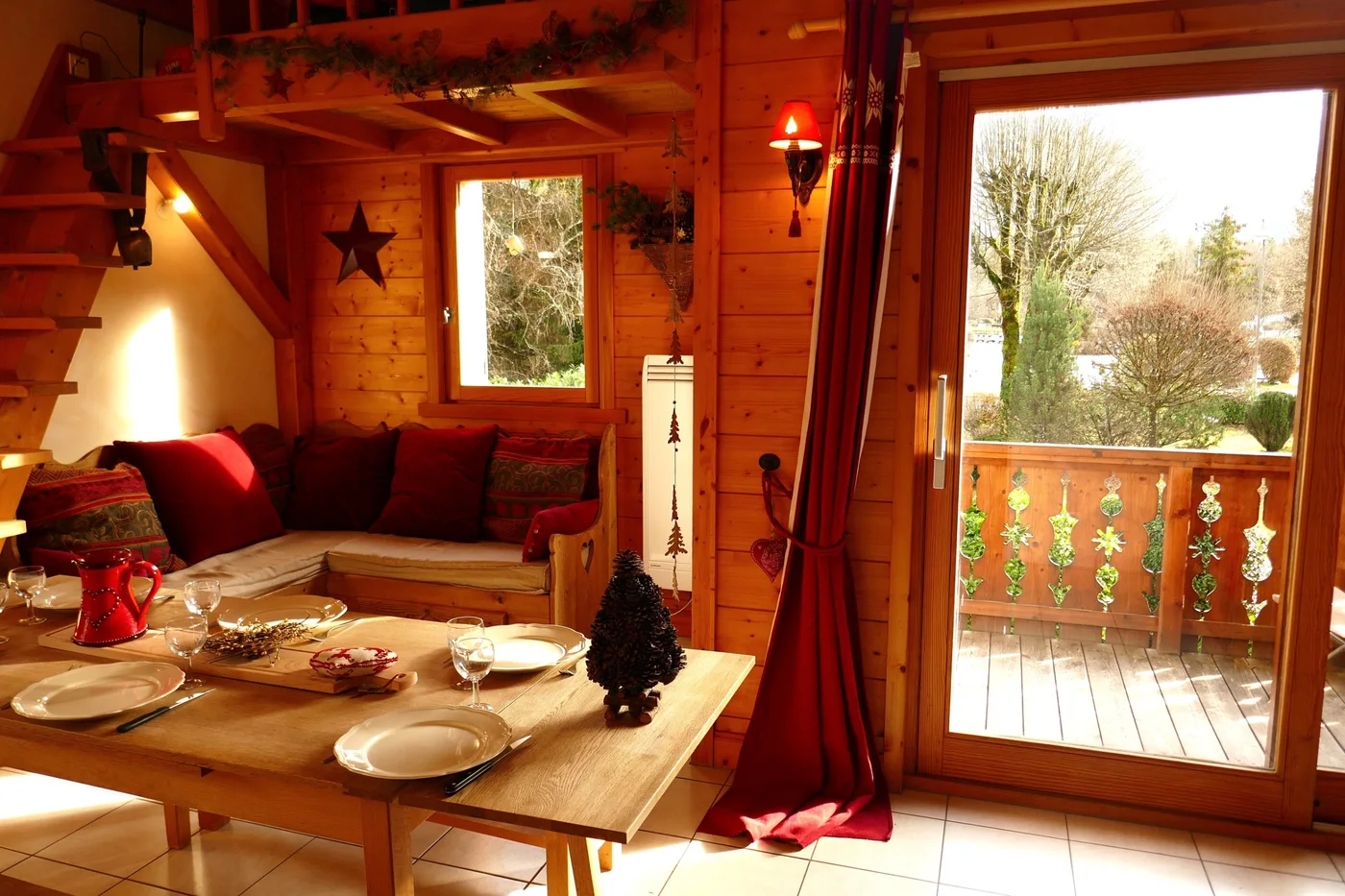 Séjour lambrissé, banquette et table dressée, porte-fenêtre ouverte sur le balcon