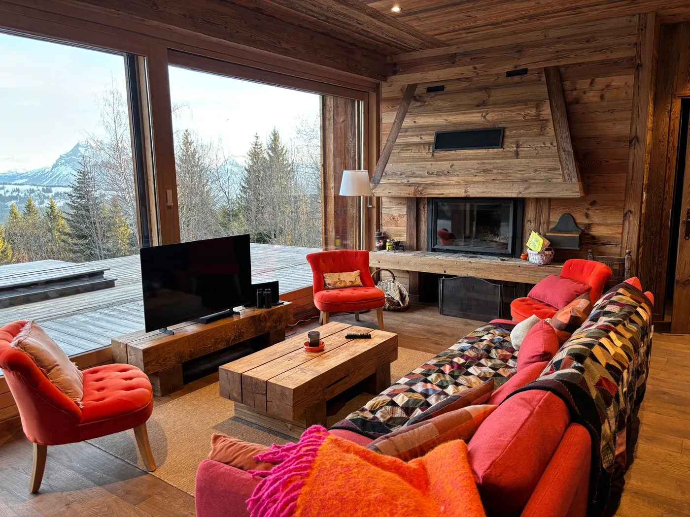 Salon avec cheminée et grandes baies ouvertes sur les montagnes