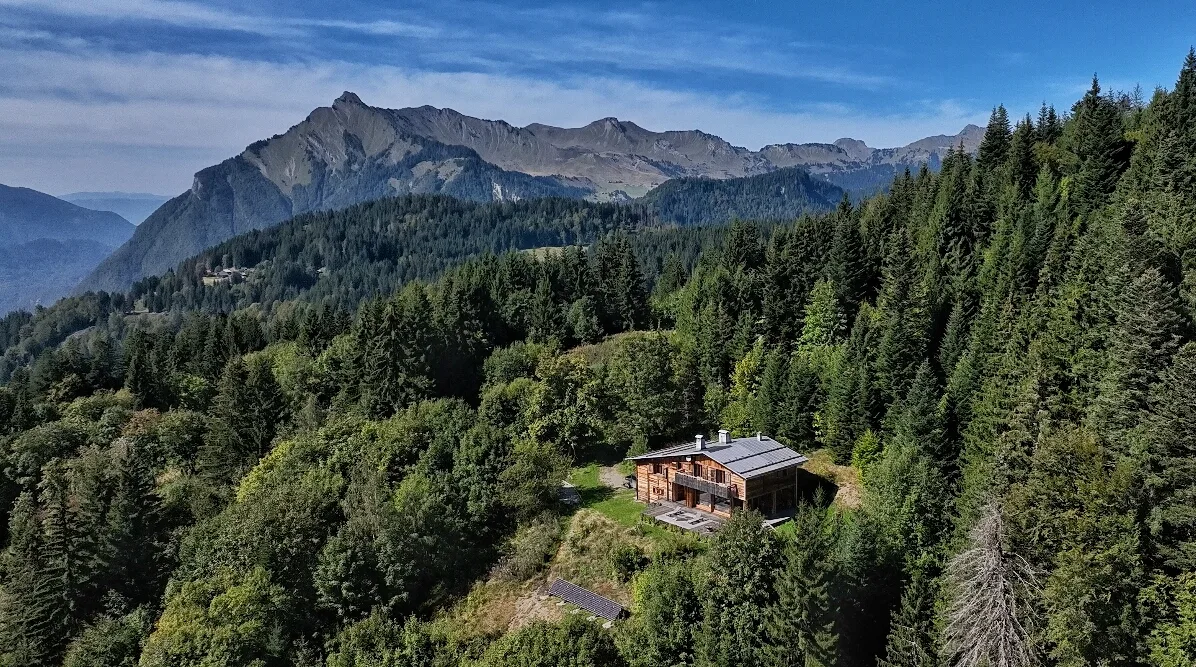 Le chalet dans la forêt au-dessus de Taninges, vue aérienne face aux sommets