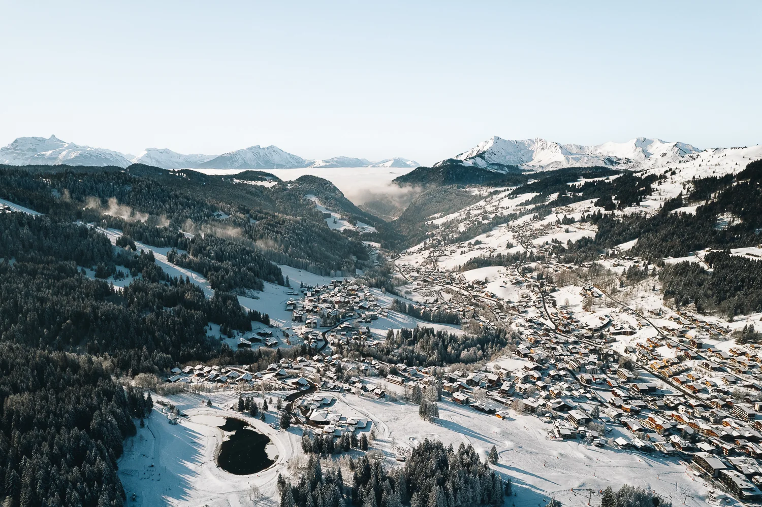 Les Gets en hiver vu du ciel : le village enneigé et ses chalets, face aux sommets